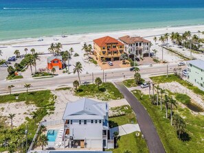 A coastal property with a swimming pool, multiple buildings, and a beach view.
