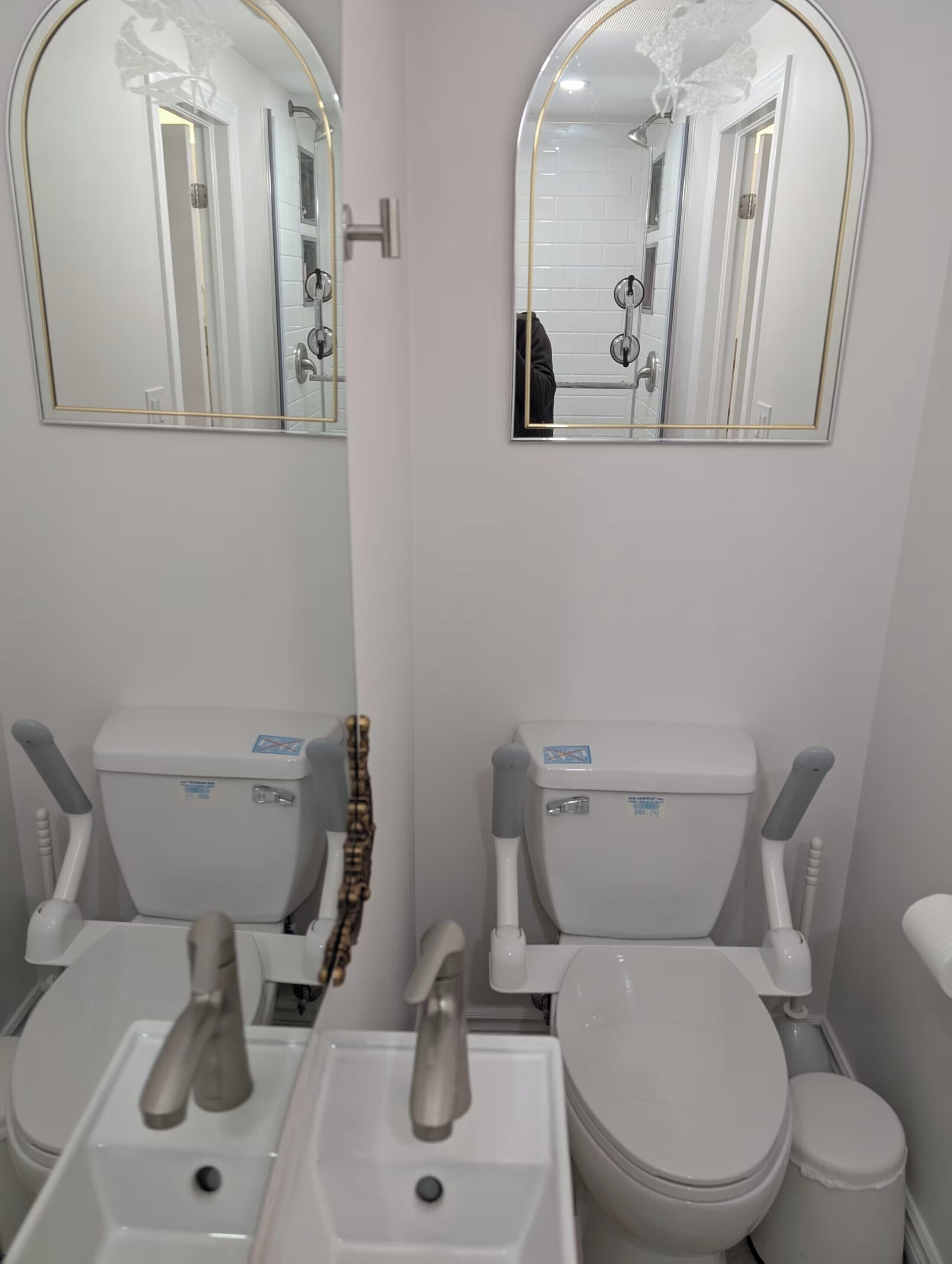 A bathroom with two toilets, a sink, and two mirrors.