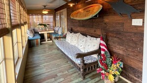 A cozy room with a wooden bench, a ceiling fan, and a surfboard decoration. - Surf Shack - Half a block from the Ocean! (South Padre Island)