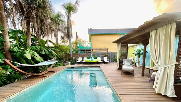 A swimming pool with a wooden deck, lounge chairs, and a hammock. - Surf Shack - Half a block from the Ocean! (South Padre Island)
