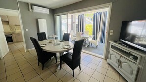Un comedor con una mesa redonda, sillas, un televisor y una cocina al fondo.