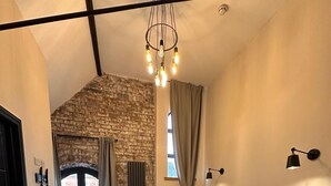 Une chambre avec deux lits, un mur en pierre, un plafond noir et une vue sur l’extérieur, visible à travers une porte.