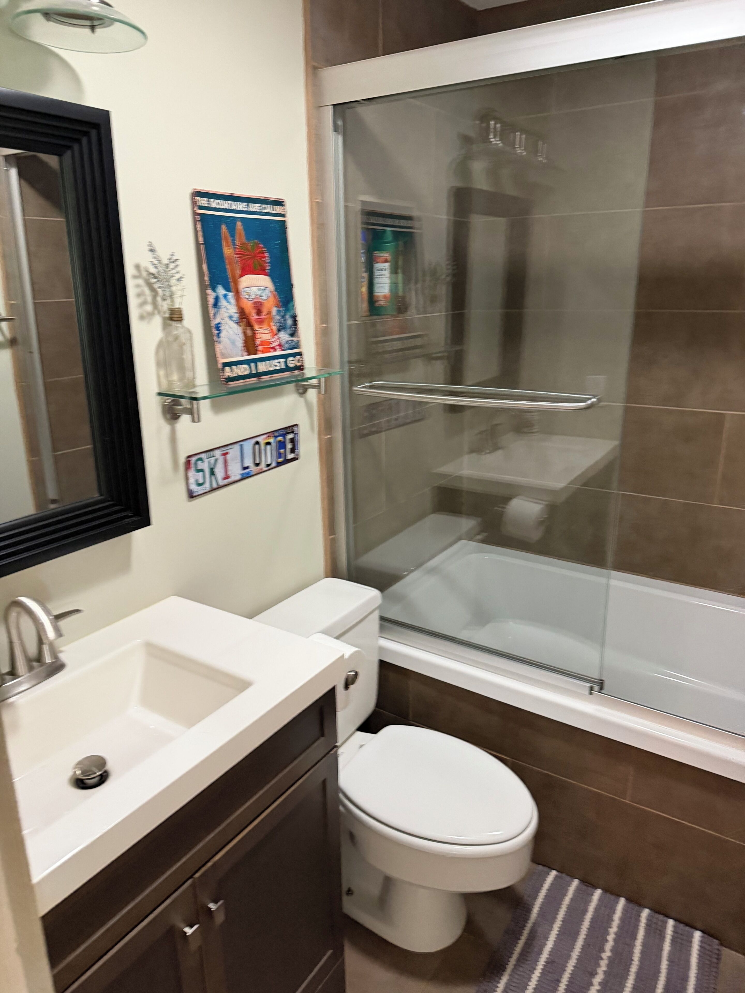 Une salle de bain avec une douche à parois de verre, un lavabo blanc et des toilettes.