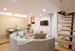 Ein modernes Wohnzimmer mit einer Couch, einem Esstisch und einem Fernseher.
