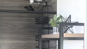 Ein Badezimmer mit dunklen Holzverkleidungen, einem schwarzen Metallregal mit einer Pflanze, einer roten Kerze und weißen Handtüchern.
