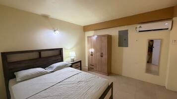 Ein Schlafzimmer mit Bett, Nachttisch, Kleiderschrank und Klimaanlage.