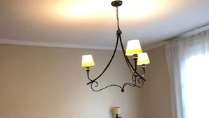 Quarto com duas camas, um candelabro e uma janela com cortinas.