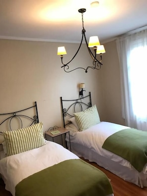 Une chambre avec deux lits, un lustre et une fenêtre avec des rideaux.