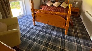 Um quarto com cama, uma cadeira, uma janela e luminária no teto.