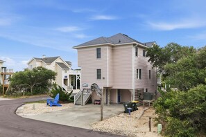 A two-story residential building with a garage, a covered outdoor area, and a small deck. - 1819 - Always Dreaming Spacious 5BR Corolla retreat with pool, hot tub, and beach access. (Corolla)