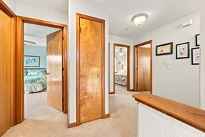 A hallway with wooden doors leading to bedrooms, a ceiling fan, and framed pictures on the wall. - 1819 - Always Dreaming Spacious 5BR Corolla retreat with pool, hot tub, and beach access. (Corolla)