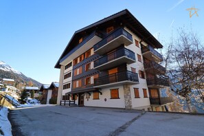 A multi-story hotel with balconies and a ski slope in the background. - Charming fully equipped studio close to the shuttle stopOutside : studio for 2 people, on the 2nd fl (St-Luc)