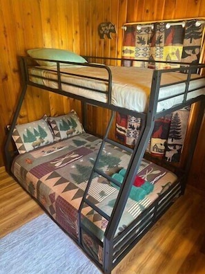 A bunk bed with a patterned bedspread and pillows, set against a wooden wall.