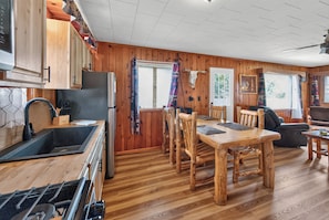 Interior de madeira com cozinha, sala de jantar e área de estar.