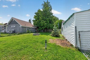 A residential backyard with a fenced area, a wooden deck, and a large tree.