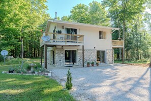 Ein zweistöckiges Haus mit Balkon, Naturstein-Fassade und einem Schotterweg.