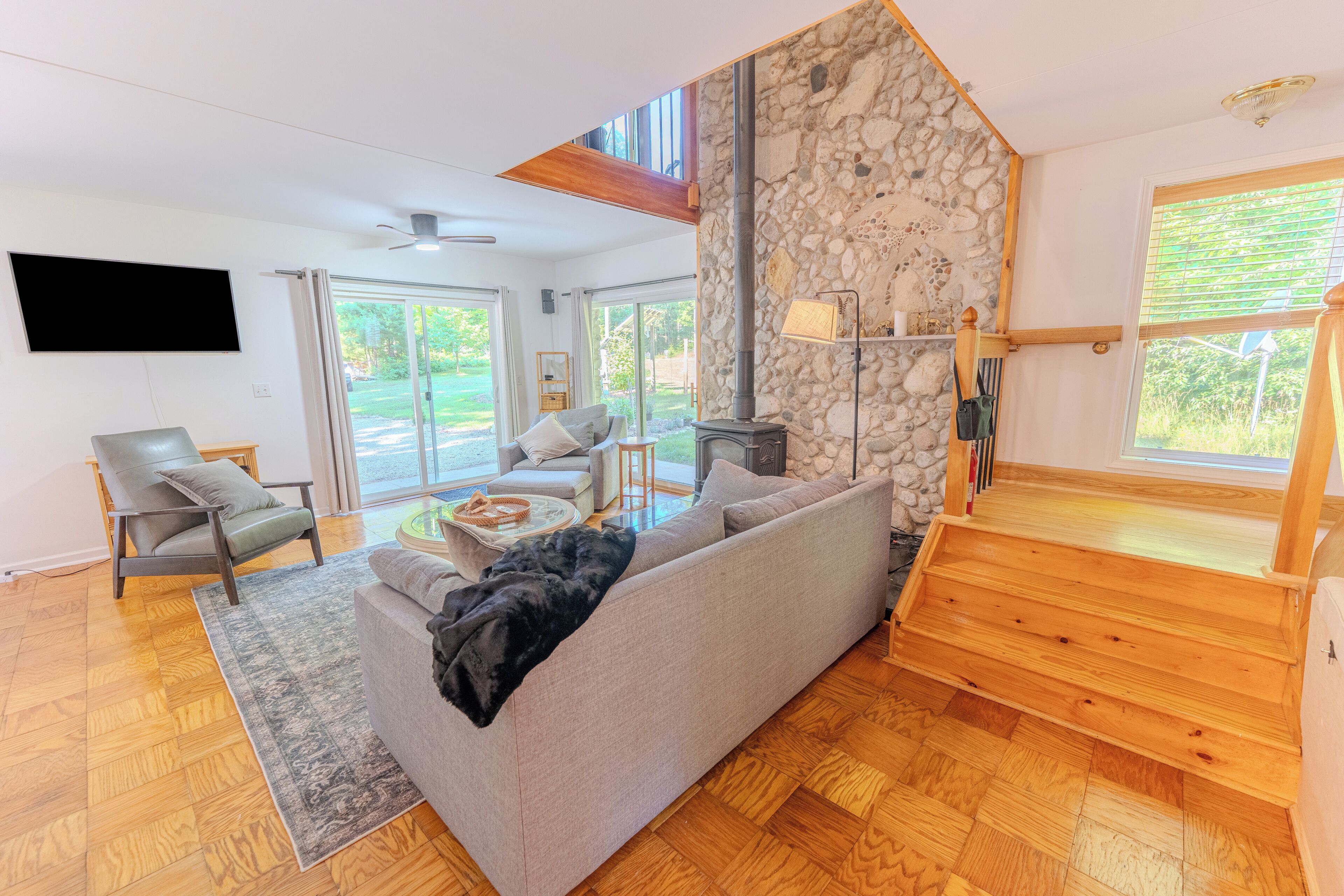 A modern living room with a stone wall, a fireplace, a sofa, and a television.