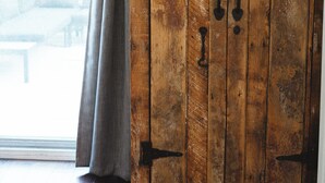 Un armario de madera con tiradores de metal y una ventana con cortinas.