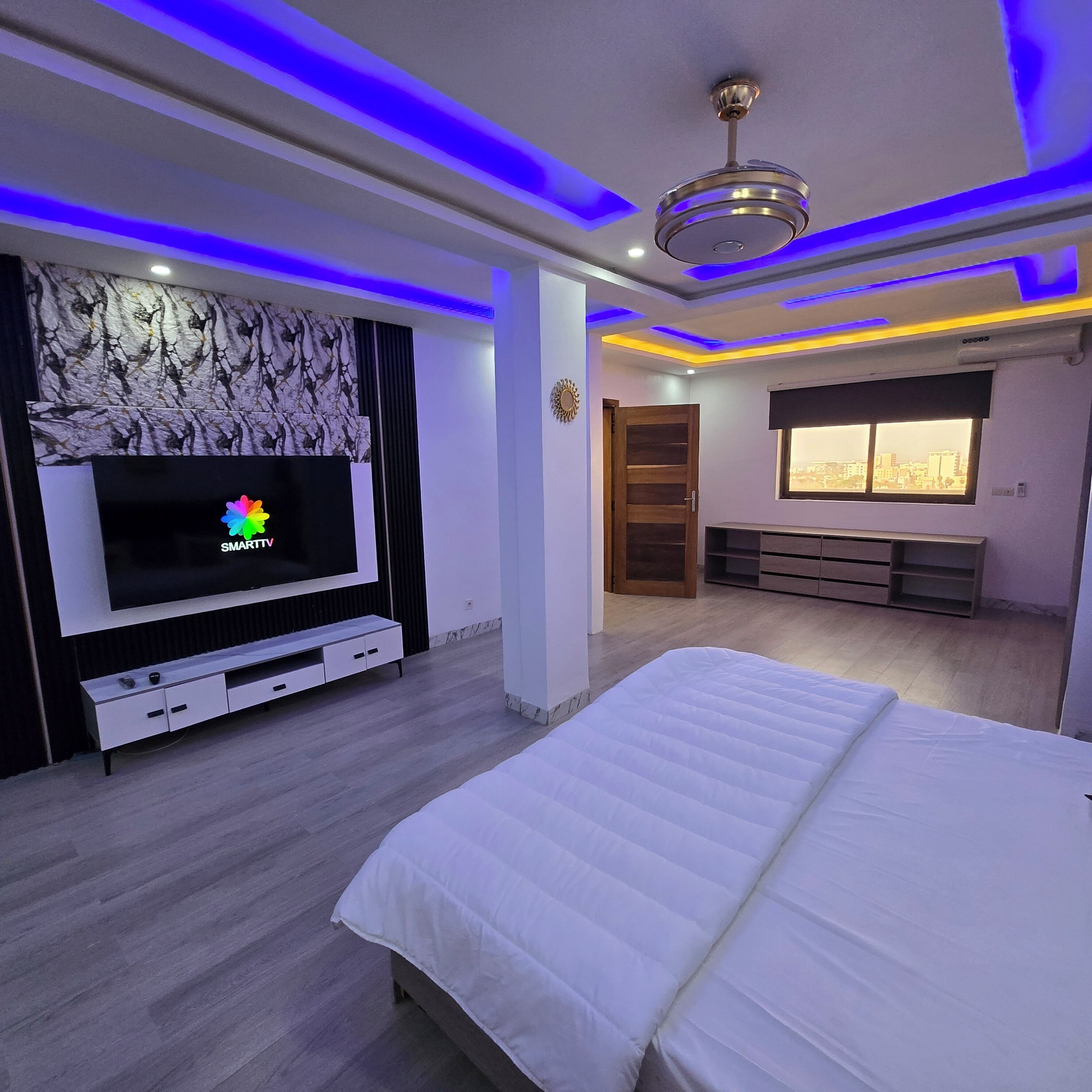 Quarto com cama, televisão, janela e vista para a cidade.