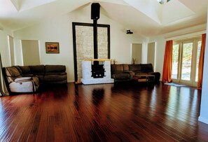 Ein Wohnzimmer mit Kamin, zwei Sofas, einem Relaxsessel und Holzdielen.