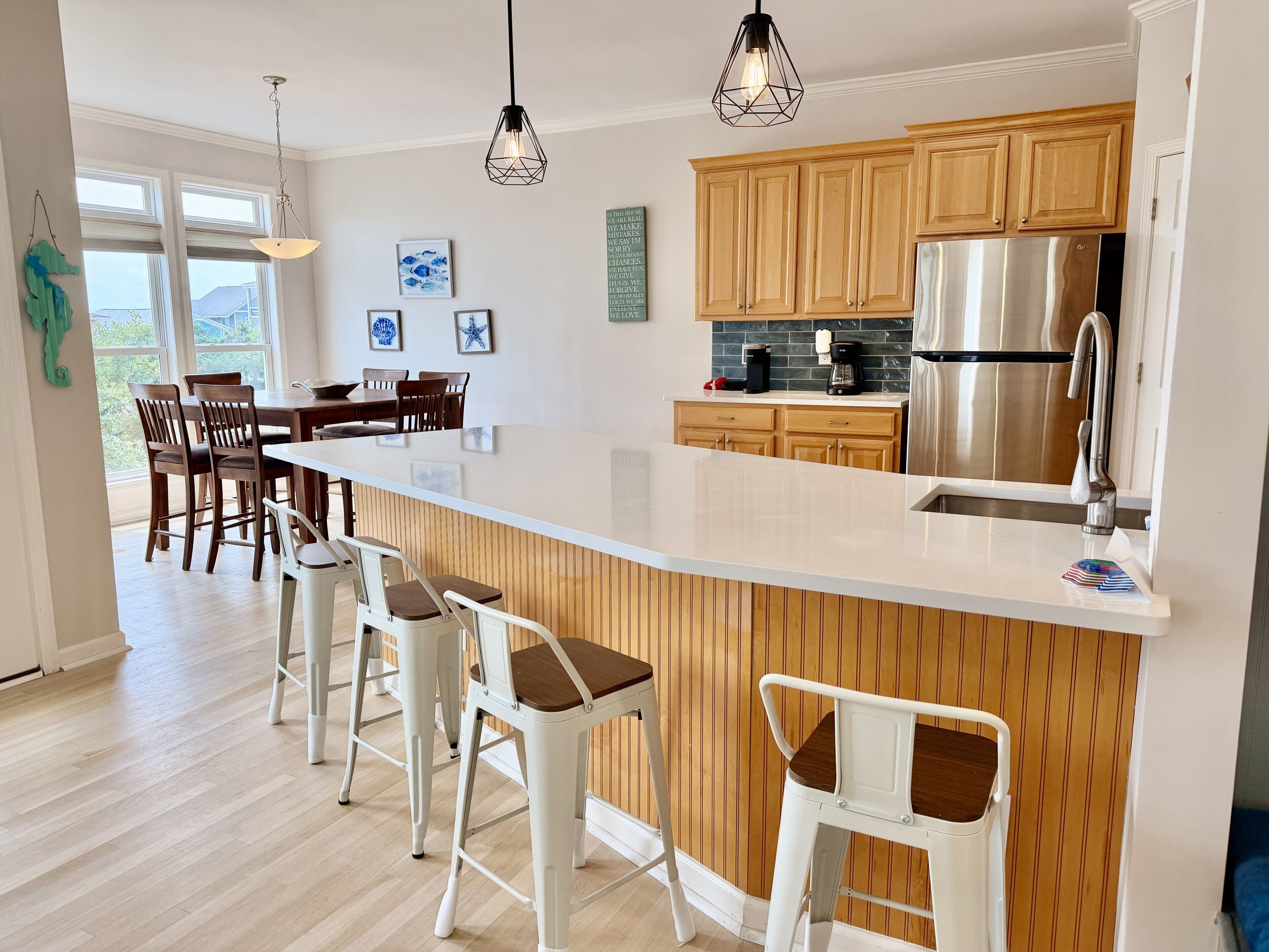 A modern kitchen with a large island, wooden cabinets, stainless steel appliances, and bar stools.
