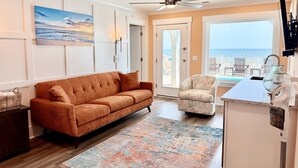 A living room with a sofa, armchair, and a view of the ocean. - Oceanfront 8BR Oak Island home with private heated pool. (Oak Island)