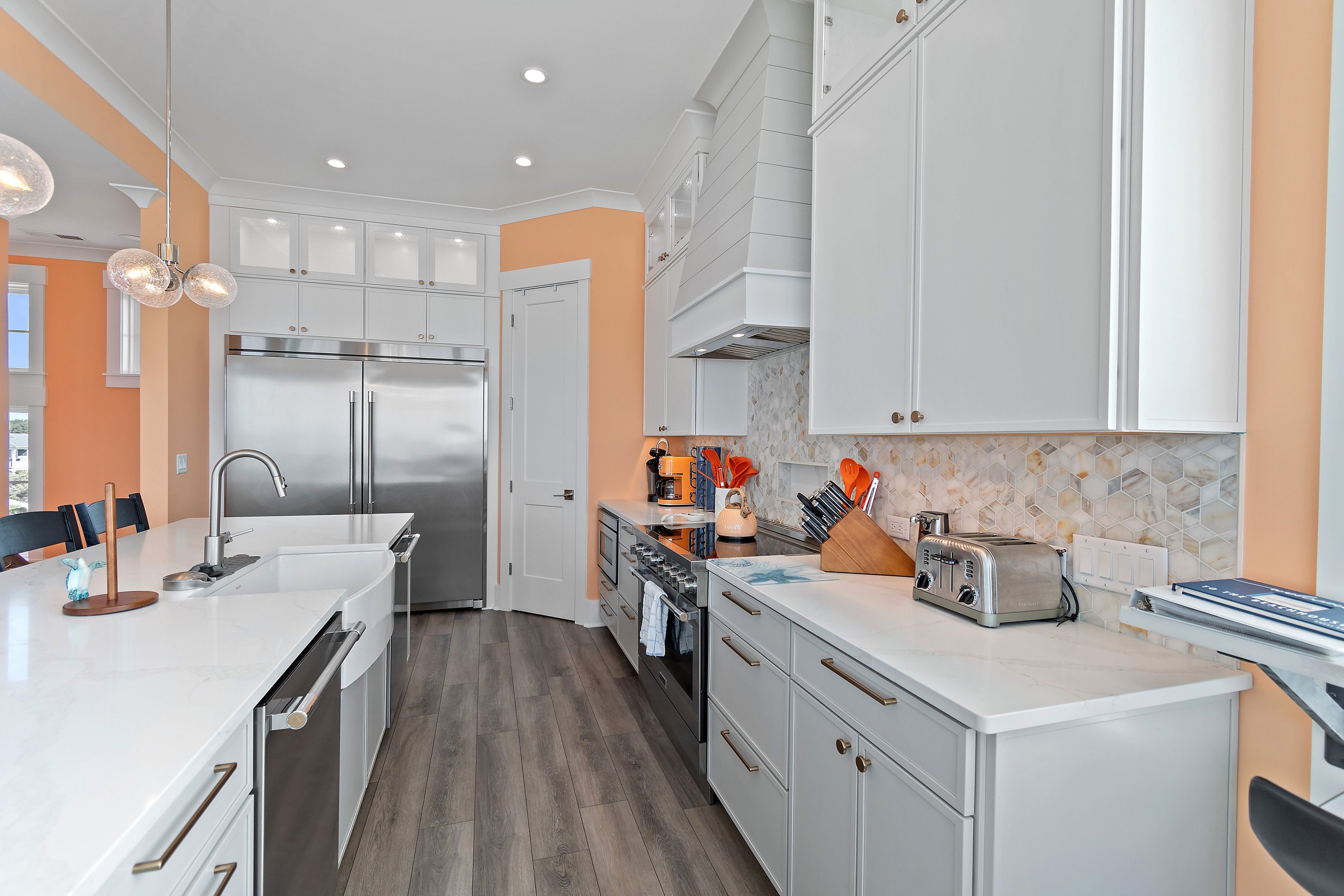 Una cocina moderna con armarios blancos, electrodomésticos de acero inoxidable y un salpicadero de azulejos.