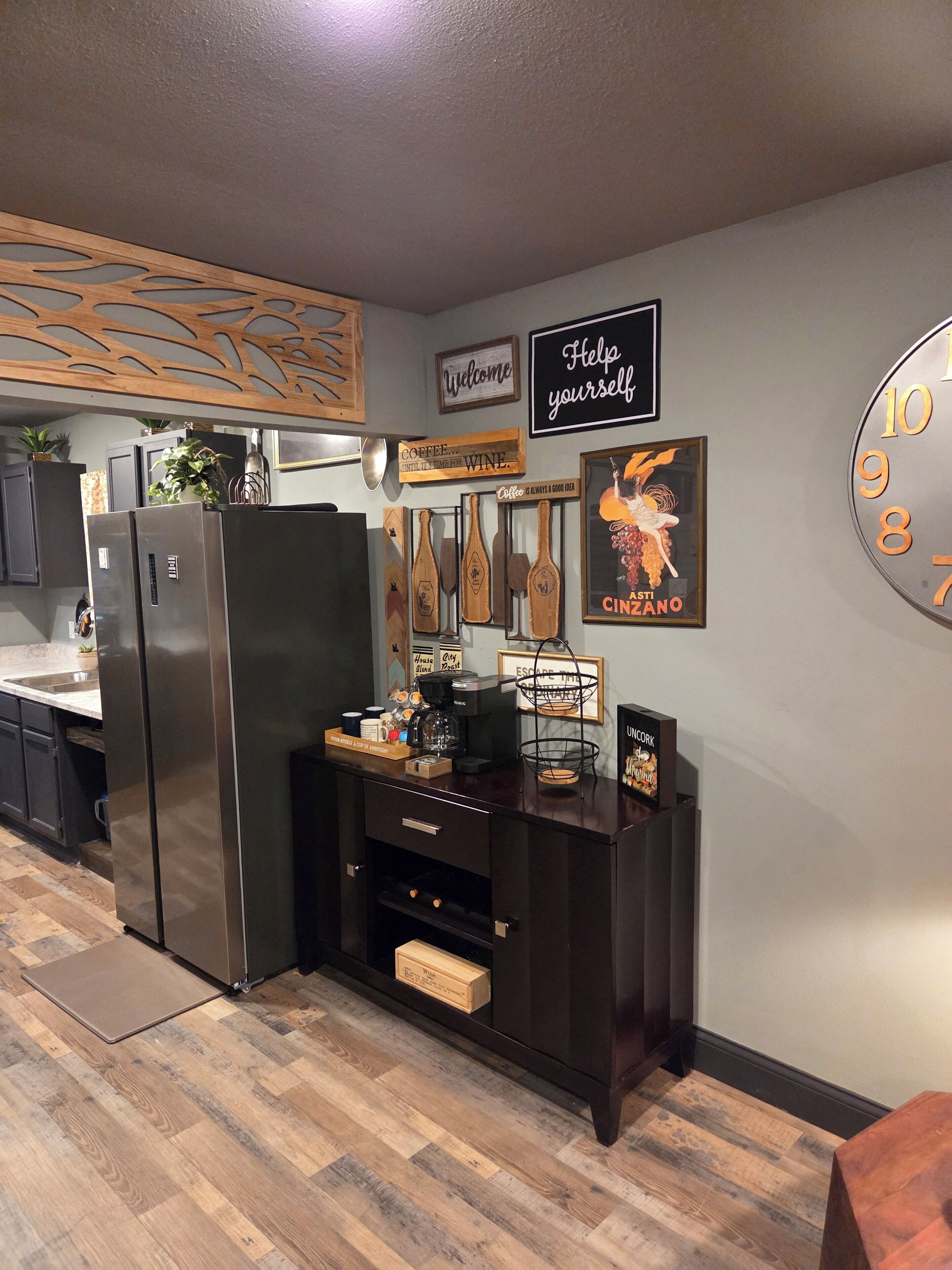 Une cuisine équipée d’un coin café, d’appareils électroménagers en acier inoxydable et de meubles de rangement en bois.