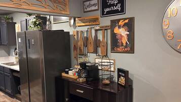 Une cuisine équipée d’un coin café, d’appareils électroménagers en acier inoxydable et de meubles de rangement en bois.
