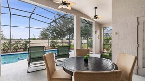 A covered patio with a pool, outdoor seating, and ceiling fans. - Windsor Palms Resort 4 Bedroom Home with Game Room (Kissimmee)