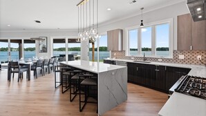 A modern kitchen with a large island, bar stools, and a view of the lake. - Waterview Oasis | Pool & hot tub| Game Room | Outdoor Kitchen (Terrell)