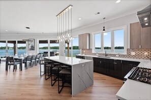 A modern kitchen with a large island, bar stools, and a view of the lake. - Waterview Oasis | Pool & hot tub| Game Room | Outdoor Kitchen (Terrell)