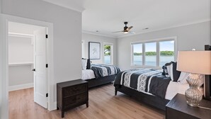 A bedroom with two beds, a ceiling fan, a nightstand, and a window with a view of the water. - Waterview Oasis | Pool & hot tub| Game Room | Outdoor Kitchen (Terrell)