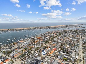 An aerial view of a coastal town with a marina, residential buildings, and a beach.