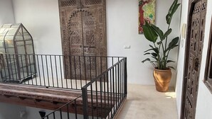 Un espacio al aire libre cubierto con un banco de madera, una planta en maceta y una puerta decorativa.