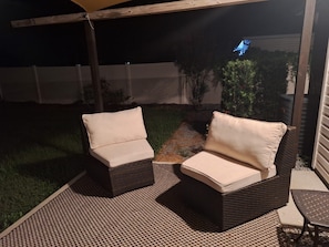 Un patio abrité comprenant deux canapés en osier et une petite table.