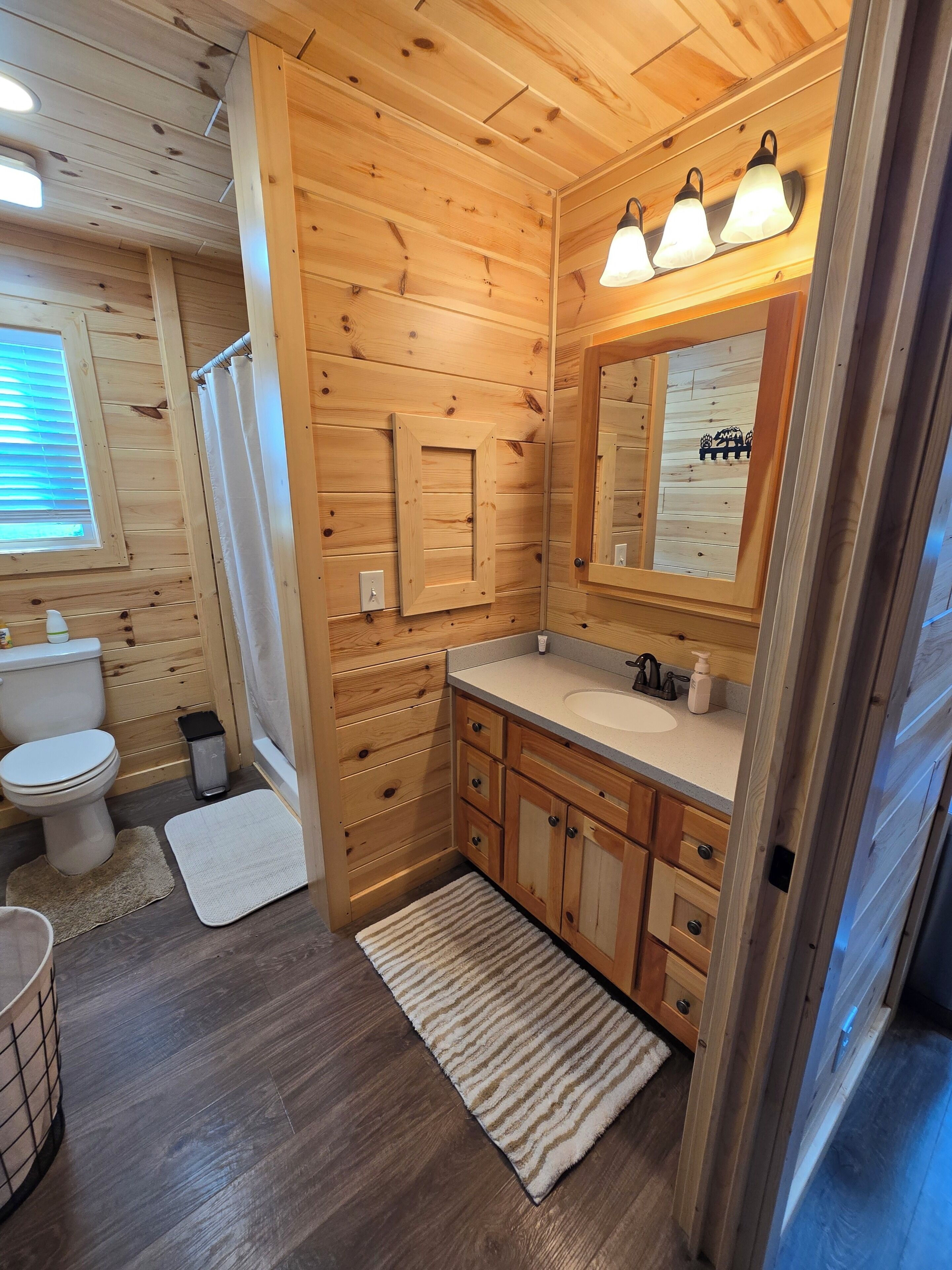 Ein Badezimmer einer Holzhütte mit Toilette, Waschbecken und Spiegel.