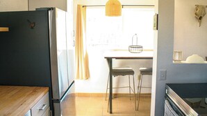 A kitchen with a refrigerator, wooden countertop, and a dining area with a table and chairs. - A cozy 532 sq ft retreat in Yucca Valley, just minutes away from Joshua Tree NP (Yucca Valley)