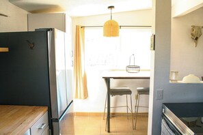 A kitchen with a refrigerator, wooden countertop, and a dining area with a table and chairs. - A cozy 532 sq ft retreat in Yucca Valley, just minutes away from Joshua Tree NP (Yucca Valley)