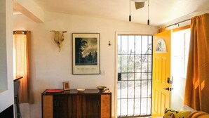 A room with a wooden cabinet, a framed picture on the wall, a door with a window, and a bed with a tiger pillow. - A cozy 532 sq ft retreat in Yucca Valley, just minutes away from Joshua Tree NP (Yucca Valley)