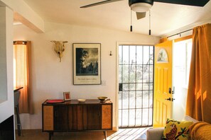 A room with a wooden cabinet, a framed picture on the wall, a door with a window, and a bed with a tiger pillow. - A cozy 532 sq ft retreat in Yucca Valley, just minutes away from Joshua Tree NP (Yucca Valley)