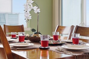 Una mesa de comedor dispuesta con platos, vasos y un florero con flores blancas.