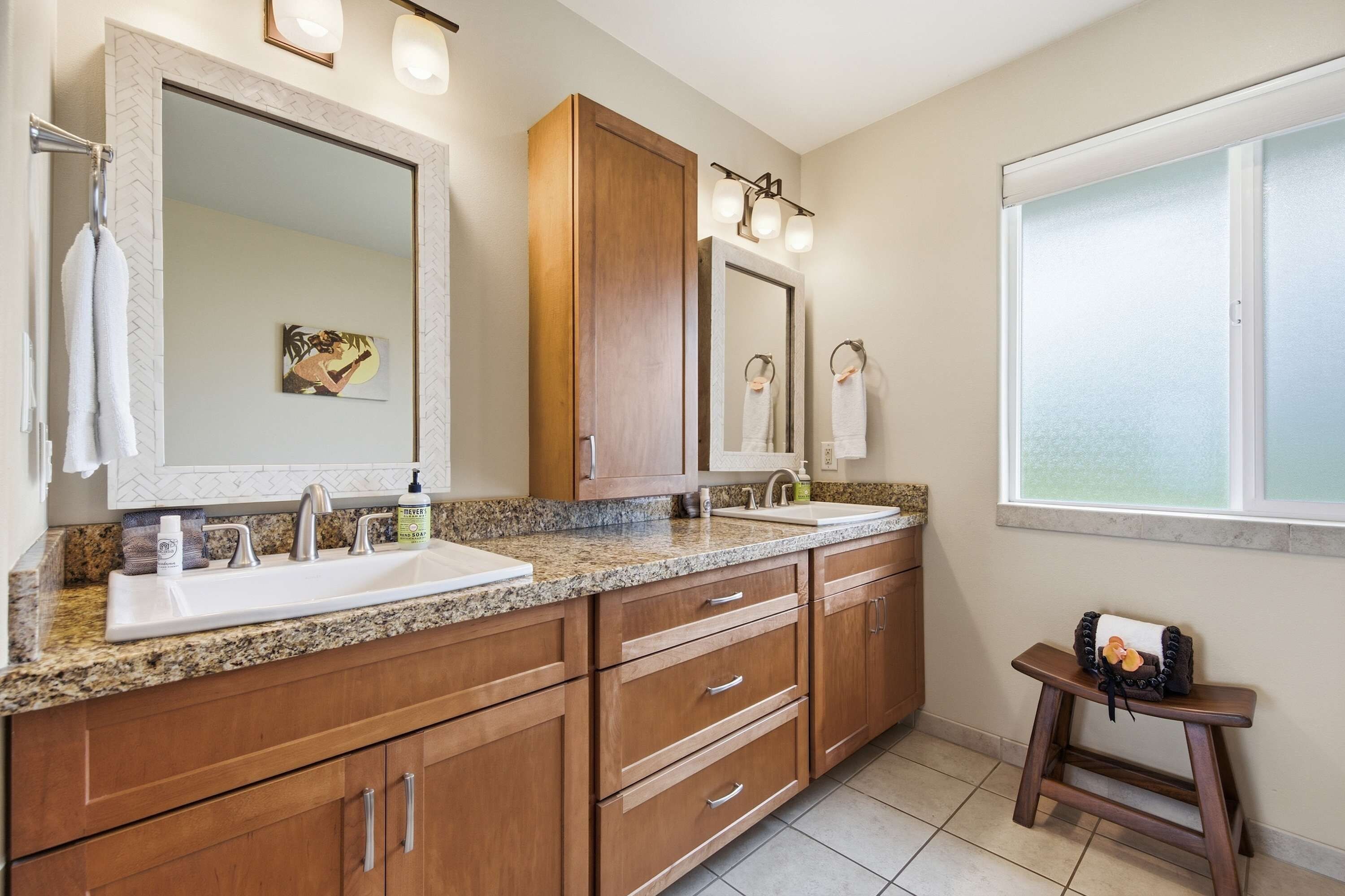 A bathroom with two sinks, wooden cabinets, a mirror, and a window.