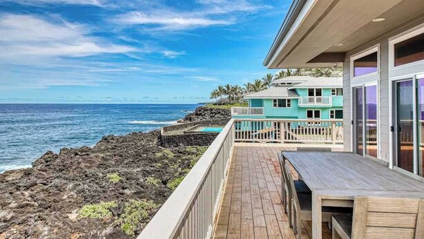 Une propriété située en bord de mer, dotée d’une terrasse en bois, d’une piscine et offrant une vue sur l’océan.