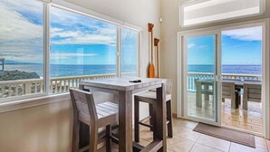 Un balcon avec vue sur l’océan, une table, des chaises et une pagaie en bois.