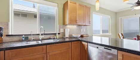 A kitchen with wooden cabinets, a stainless steel dishwasher, and a large window.