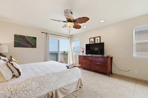 A bedroom with a bed, a dresser, a television, and a ceiling fan. - *NEW* Pahoa Oceanfront Home for Sunrise and Rugged Coast Days (Pahoa)