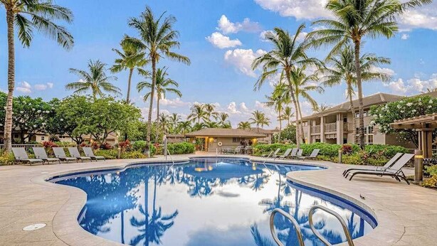 A swimming pool with lounge chairs, palm trees, and a building in the background. - *NEW* Fall Special Pool and Tennis Days Near Anaeho'omalu Bay (Waikoloa)