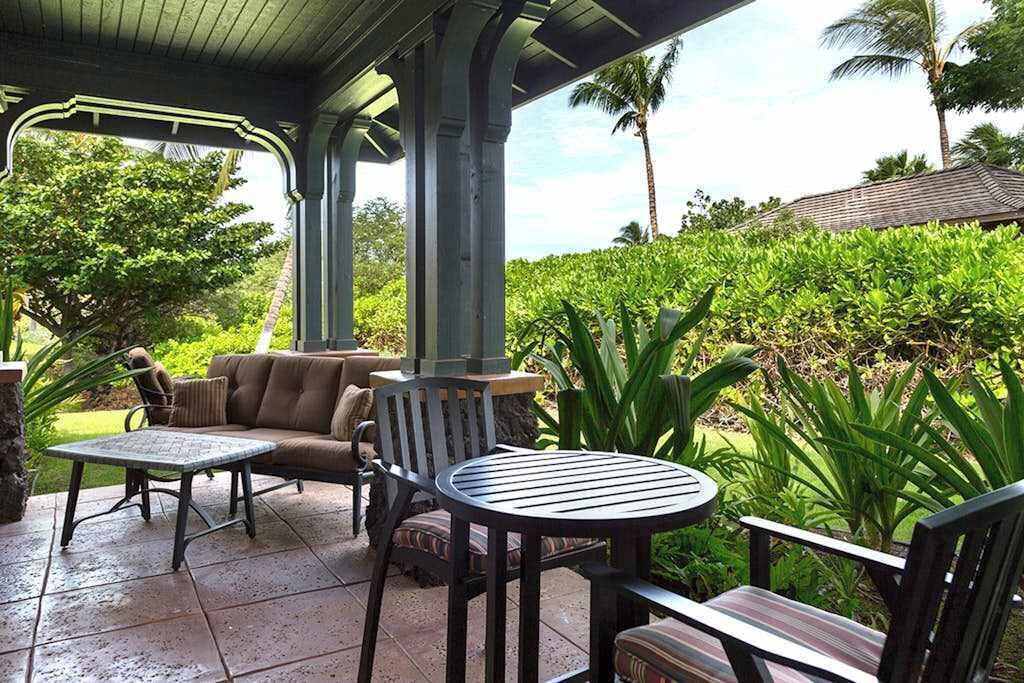 Une terrasse extérieure dotée d’un espace salon couvert, d’une table ronde et d’un canapé.