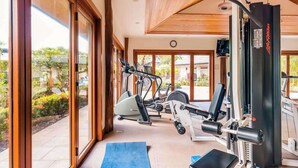 A gym with exercise equipment, large windows, and a view of the outdoors. - NEW Mauna Lani Space, Pool Time, and Kohala Coast Sun (Waimea)